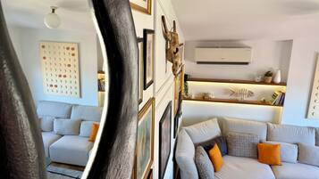 A living room with a sofa, a coffee table, and a wall-mounted shelf with decorative items.
