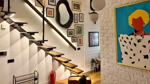 A staircase with wooden steps and black railings, a fire extinguisher, and various framed artworks on the walls. - The Genoese Galata (İstanbul)