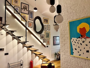 A staircase with wooden steps and black railings, a fire extinguisher, and various framed artworks on the walls. - The Genoese Galata (İstanbul)