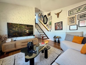 A living room with a TV, sofa, coffee table, and artwork on the walls.