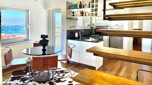 A modern kitchen with a view of the city, a dining area with a table and chairs, and a staircase. - The Genoese Galata (İstanbul)