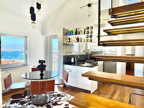 A modern kitchen with a view of the city, a dining area with a table and chairs, and a staircase. - The Genoese Galata (İstanbul)