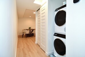 A laundry room with a washing machine and dryer, a table with chairs, and a door with louvered panels. - 2 Bedroom 2 Bathroom Walker and Transit Paradise on H Street Corridor (Washington)