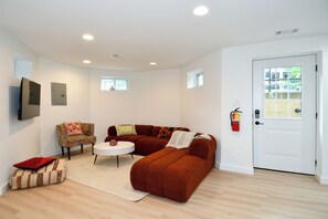 A living room with a brown sofa, a round coffee table, a patterned armchair, and a white door with a window. - 2 Bedroom 2 Bathroom Walker and Transit Paradise on H Street Corridor (Washington)