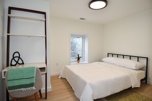 A bedroom with a bed, a desk, a chair, a window, and a potted plant. - 2 Bedroom 2 Bathroom Walker and Transit Paradise on H Street Corridor (Washington)