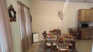 A dining area with a table, chairs, a decorative wall piece, a microwave, and cabinets.