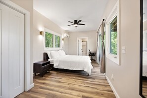 Ein Schlafzimmer mit einem Bett, einem Deckenventilator und Blick ins Freie.