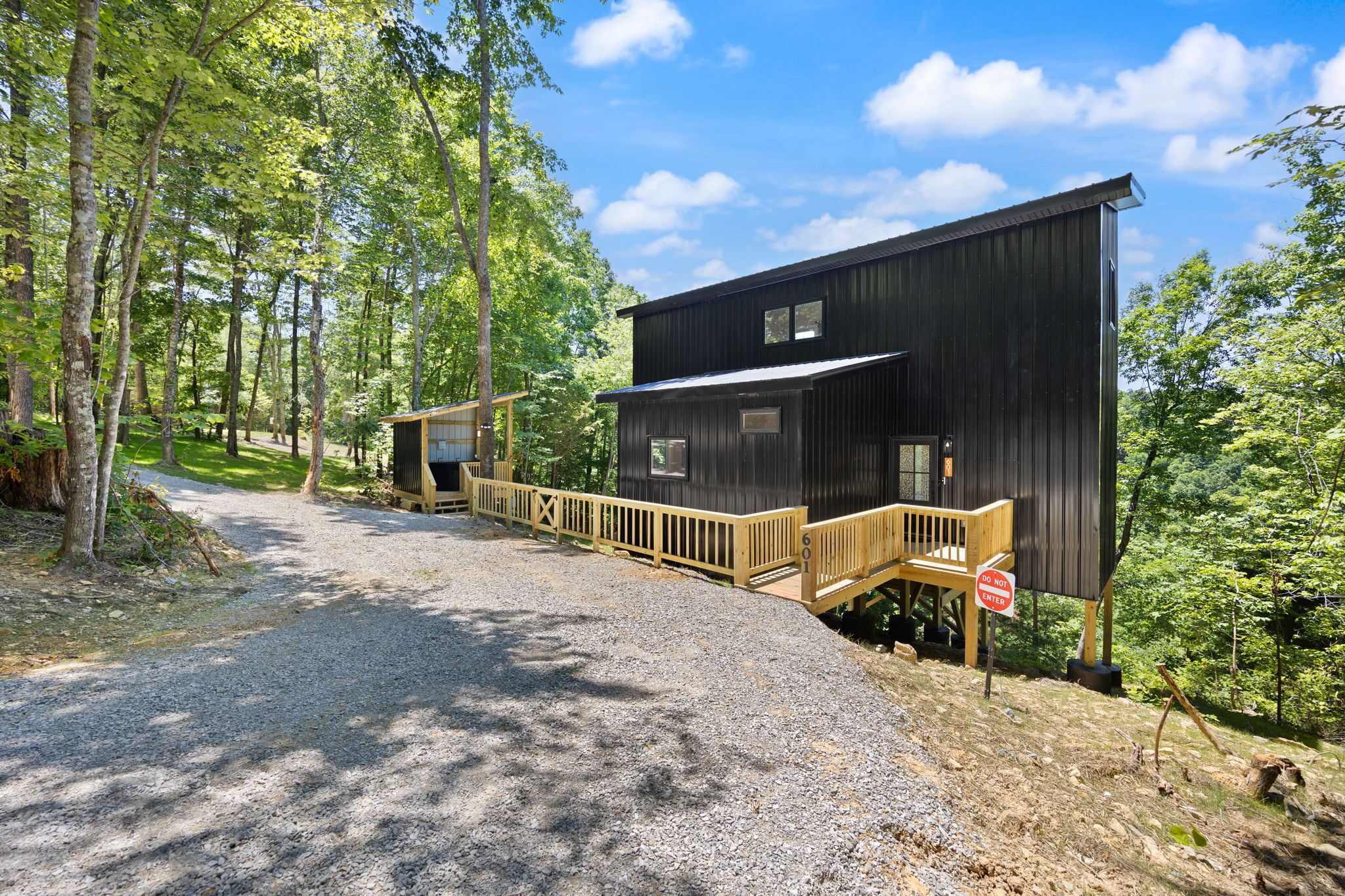 A cabin with a wooden deck and a gravel path leading to it.