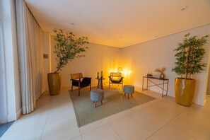 Ein modernes Wohnzimmer mit einer Couch, zwei Sesseln, einem Couchtisch und zwei Zimmerpflanzen.