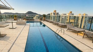 Una piscina sul tetto con acqua cristallina, circondata da sdraio e vista sulla città.