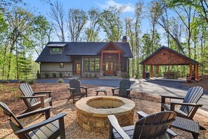 A lodge with a stone fire pit, outdoor seating, and a covered area. - The Lake Escape-Where Fire-pit Meets Hot-tub (Tiger)