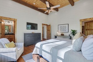A bedroom with a bed, a dresser, a TV, and a ceiling fan. - The Lake Escape-Where Fire-pit Meets Hot-tub (Tiger)