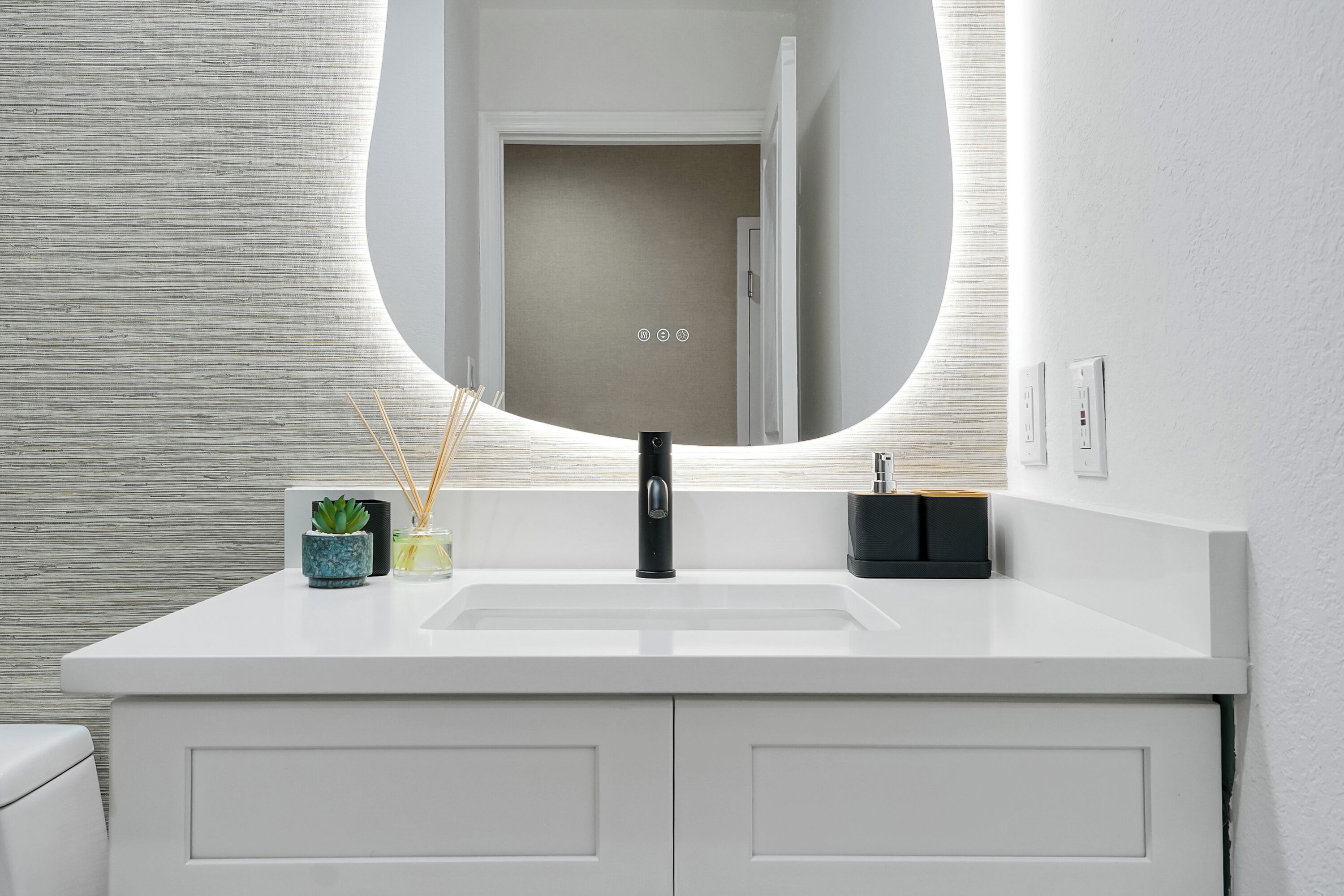 Une salle de bain moderne avec un meuble-lavabo blanc, un miroir rond et un évier.