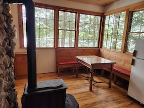A cabin interior with a wooden table, bench, and a stove.