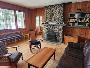 L’intérieur chaleureux d’un chalet avec une cheminée en pierre, des meubles en bois et une bibliothèque.