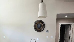 A kitchen island with a sink, a pendant light, and a decorative wall clock. - Moab Beauty Custom Home (Moab)