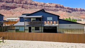 A modern two-story house with a balcony, a garage, and a wooden fence. - Moab Beauty Custom Home (Moab)