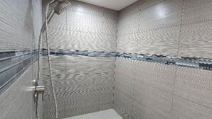 A small, tiled shower room with a handheld showerhead and a built-in seat. - Moab Beauty Custom Home (Moab)