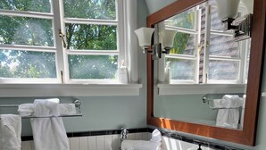 Un baño con un espejo grande, baldosas blancas, encimera negra y un inodoro.