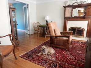 A living room with a dog, wooden furniture, a patterned rug, and a fireplace. - Family Favourite in Kitsilano.  Outdoor Gym and large cedar deck. (Vancouver)