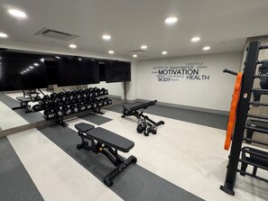 Ein Fitnessraum mit Kurzhanteln, Langhantelbank und einer Wand mit motivierenden Sprüchen.