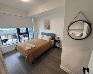 Ein Schlafzimmer mit Bett, Nachttisch, Spiegel und Fenster mit Ausblick.