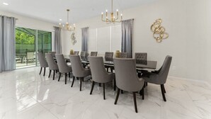A dining area with a long table, multiple chairs, and a chandelier. - 12BR/11BA Home w/Private Pool Near Parks (MA36) (Kissimmee)