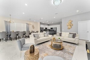 Ein modernes Wohnzimmer mit Essbereich, einer Küche im Hintergrund und einer Chandeliebre.