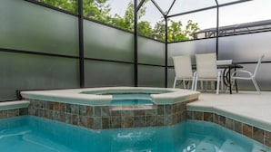 A swimming pool with a hot tub, surrounded by a covered patio with chairs and a table. - 12BR/11BA Home w/Private Pool Near Parks (MA36) (Kissimmee)