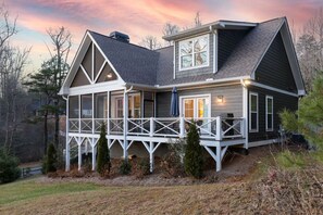 Une maison à deux étages avec un porche, une cheminée et une grande fenêtre.