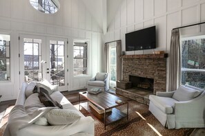 A spacious living room with a fireplace, white furniture, and large windows. - Elegant Murray Cove at Lake Burton (Tiger)