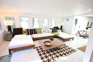 Uma sala de estar moderna com sofá, duas camas, uma mesa de centro e um tapete estampado.