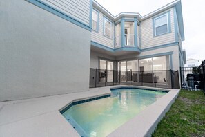 Ein Wohnhaus mit Swimmingpool, einer überdachten Terrasse und einer großen Glasdoor, die zu einem Innenbereich führt.