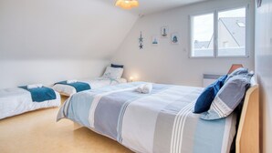 Una camera da letto con due letti, un soffitto spiovente e una finestra vista.