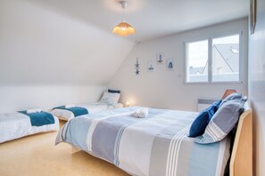 A bedroom with two beds, a sloped ceiling, and a window with a view. - Les Azurs d'Erdeven - Terrasse - Jardin (Erdeven)