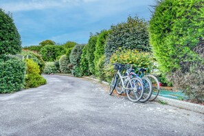 A paved road flanked by neatly trimmed hedges and a bicycle parked on the side. - Les Azurs d'Erdeven - Terrasse - Jardin (Erdeven)