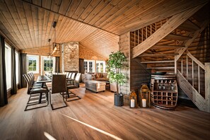 A spacious room with wooden floors, a long dining table, and a staircase. - The Nordic Retreat - Stryn (Vestland)