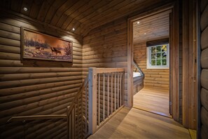 A wooden interior with a staircase, a framed picture, and a window.