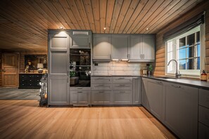 A modern kitchen with wooden flooring, built-in cabinets, and a window.
