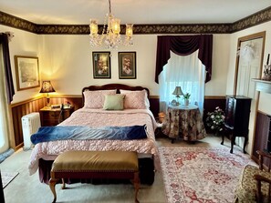A bedroom with a large bed, a chandelier, a round table with a lamp, and a cabinet. - Perfect 2-bedroom house w/ AC in peaceful Tracy City on The Mountain Goat Trail (Tracy City)