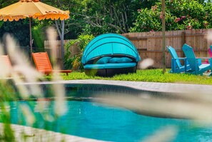 A backyard with a swimming pool, a blue outdoor seating area, and a wooden fence. - Sports Court,  Heated Pool, Mini Golf, Fire Pit, Game Room in Bradenton (Bradenton)
