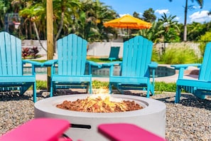 A fire pit with chairs around it, a yellow umbrella, and greenery in the background. - Heated Pool, Sports Court, Mini Golf, Firepit (Bradenton)
