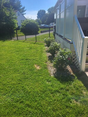 A well-maintained lawn, a black metal fence, and a white building with a visible garage door. - Cozy 1-bedroom apartment in lovely Saint Georges with AC (Saint Georges)