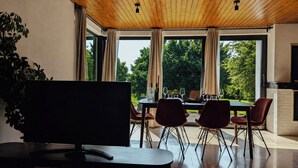Uma área de refeições moderna com uma mesa grande, cadeiras e uma televisão.