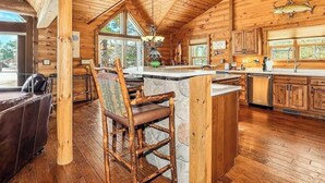 A wooden cabin interior with a dining area, kitchen, and large windows. - Luxury log cabin on Spider Lake in Manitowish Waters (Manitowish Waters)