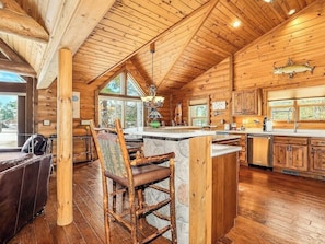 Ein Holzblockhaus-Interieur mit Essbereich, Küche und großen Fenstern.