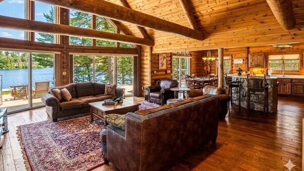 A spacious log cabin interior with a large living area, wooden beams, and a view of a lake. - Luxury log cabin on Spider Lake in Manitowish Waters (Manitowish Waters)