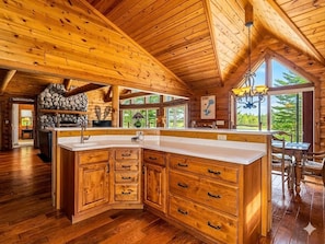 Eine geräumige Küche mit Holzausstattung, einer großen Kochinsel und einem Kamin aus Stein.