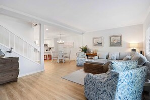 Ein modernes Wohnzimmer mit Treppe, Essbereich und einer Küche im Hintergrund.