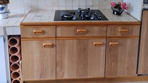 Una cocina con armarios de madera, estufa a gas y salpicadero azulejado.